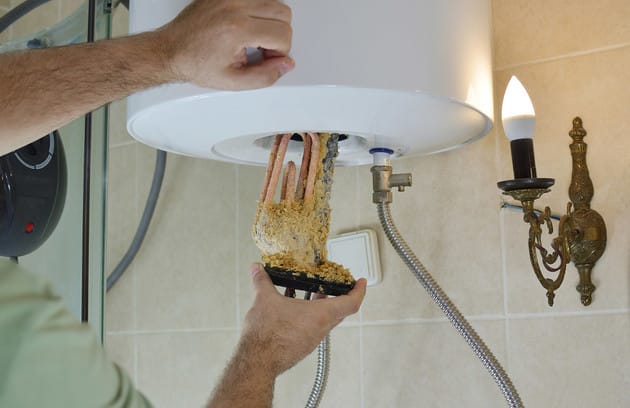 Technician removing mineral buildup from a water heater in Jacksonville